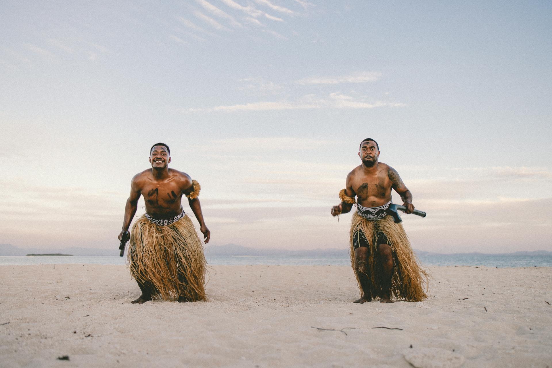 Two people in traditional garments standing on a beach