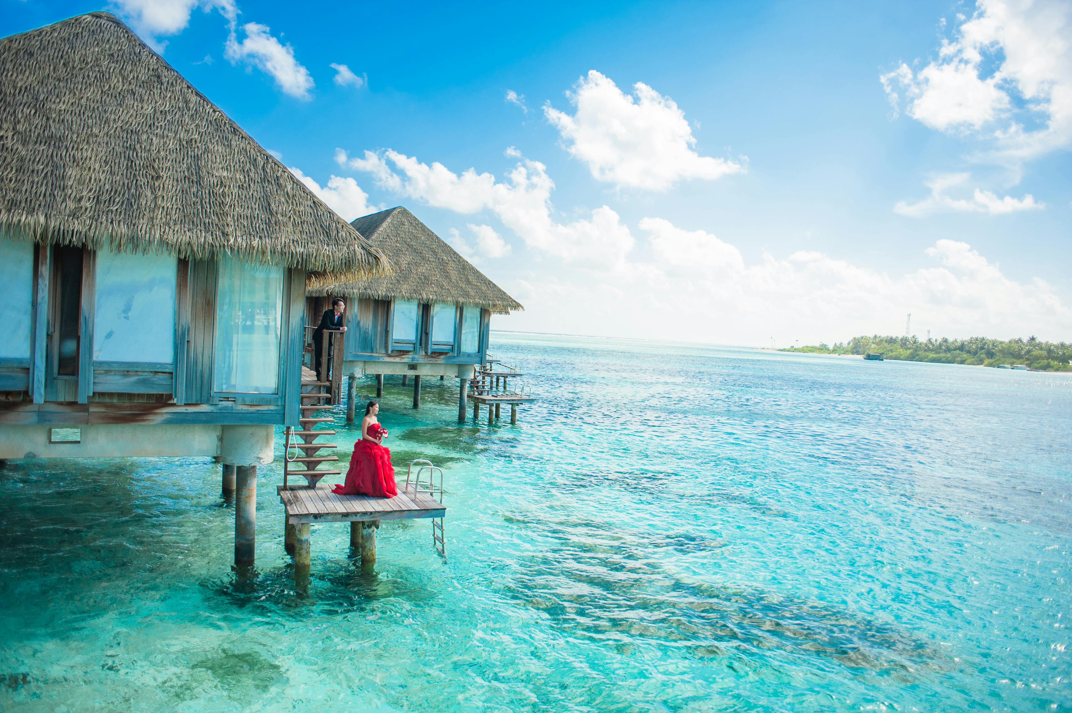 A woman standing on a platform attached to an overwater bungalow overlooking the ocean and sea