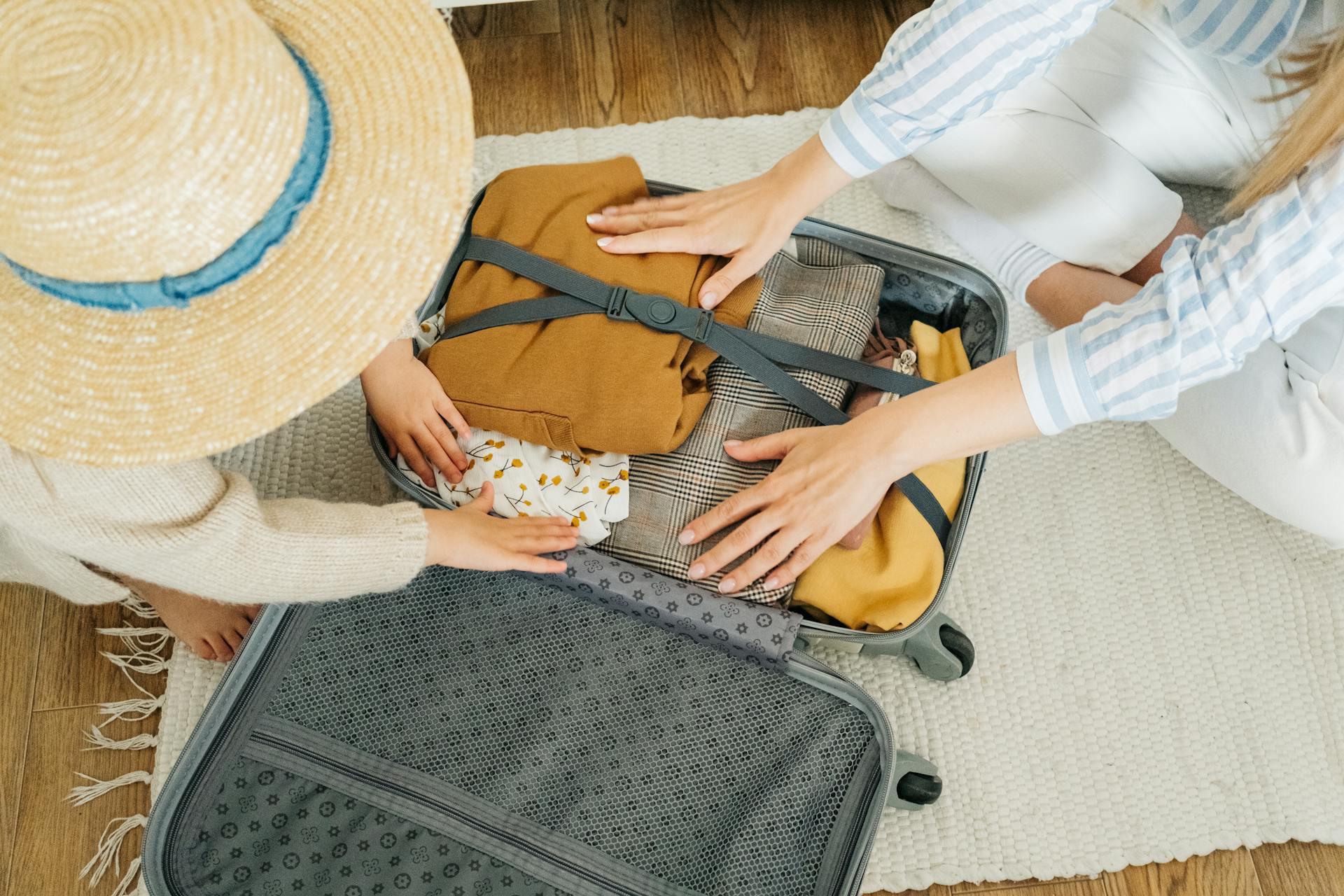 Two people packing clothes in a suitcase