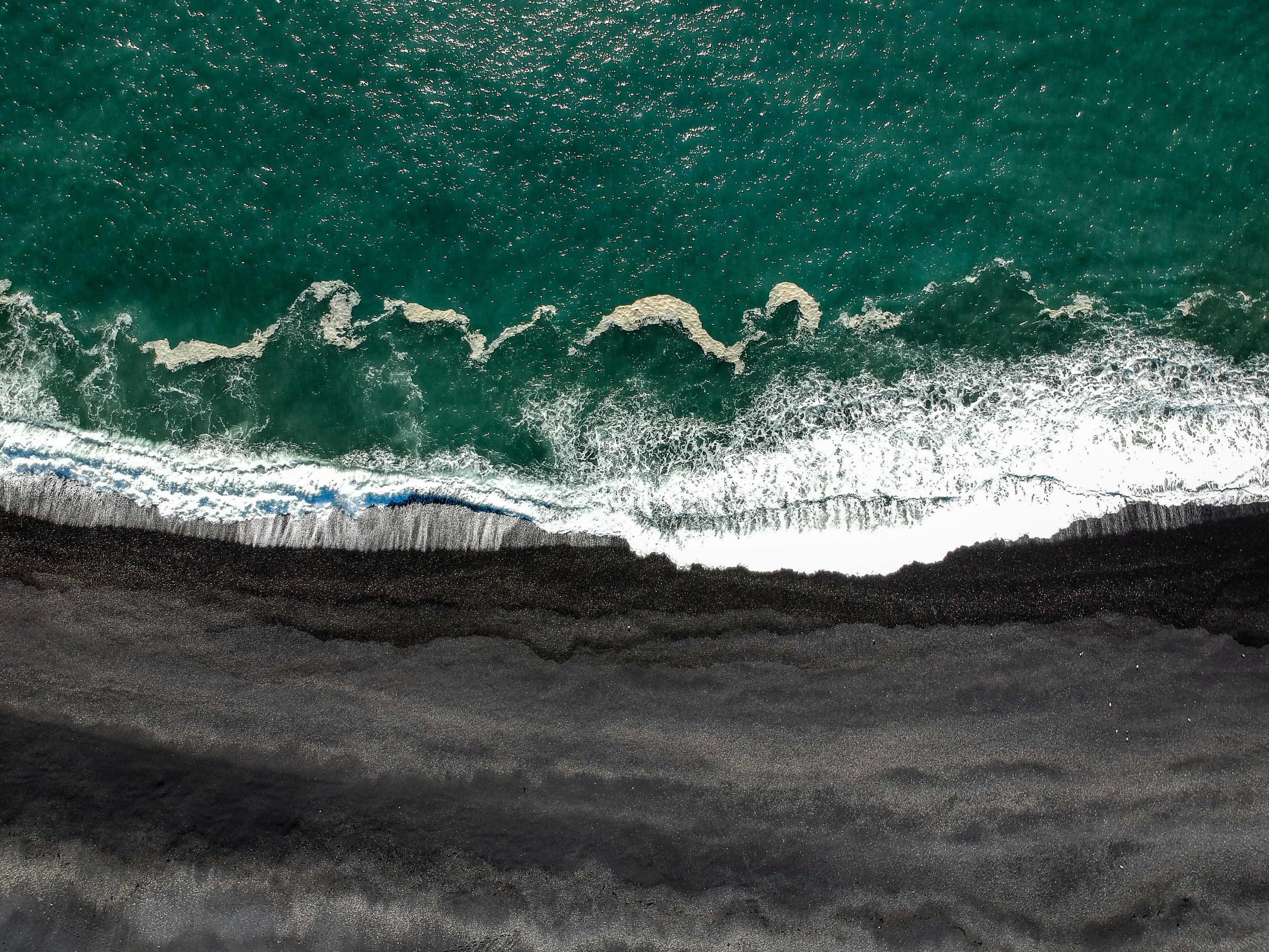An ocean shoreline with black sand