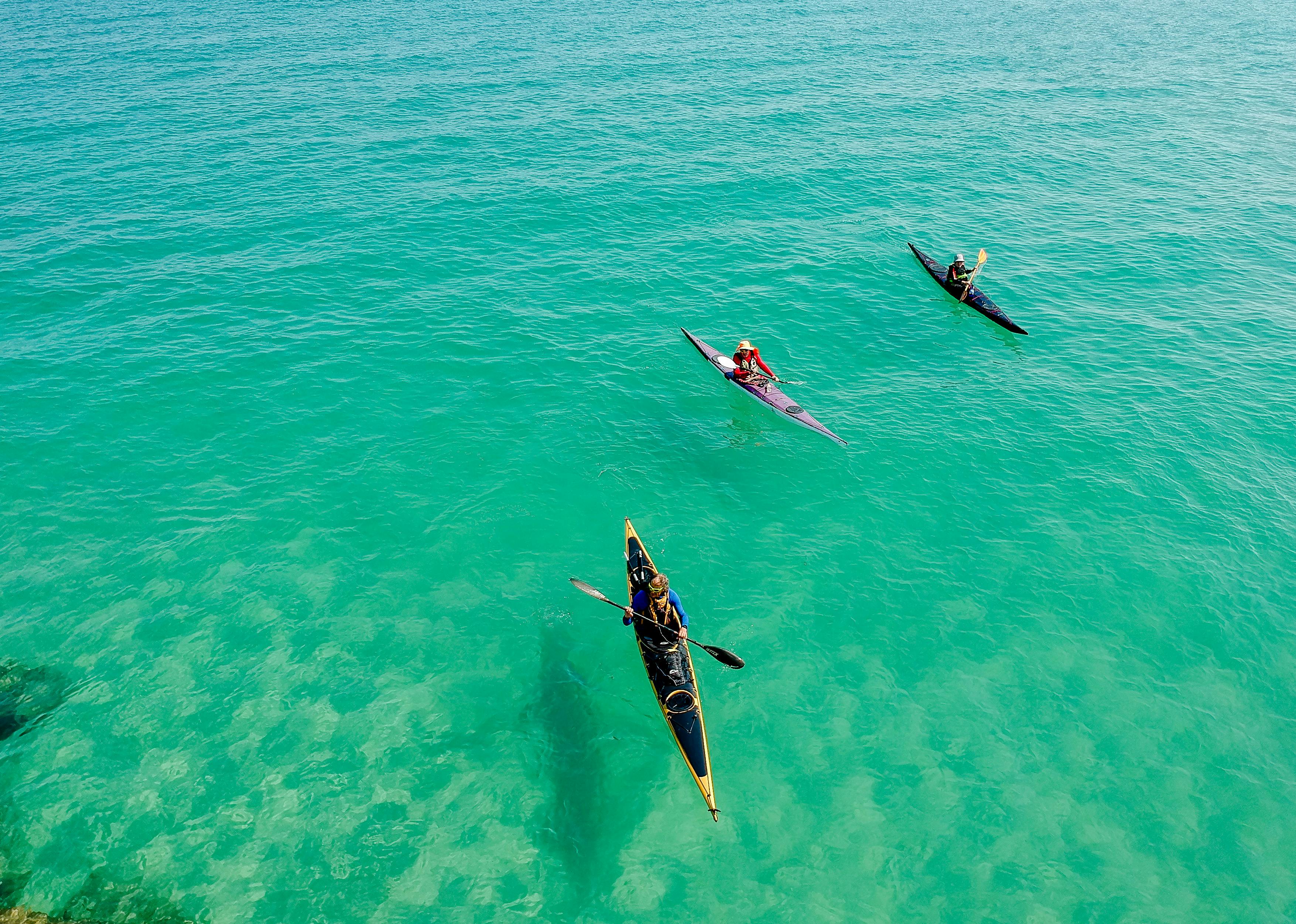 Three kayaks floating at sea